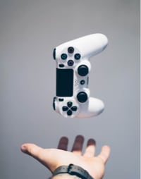 An image of a hand holding a floating PlayStation controller.